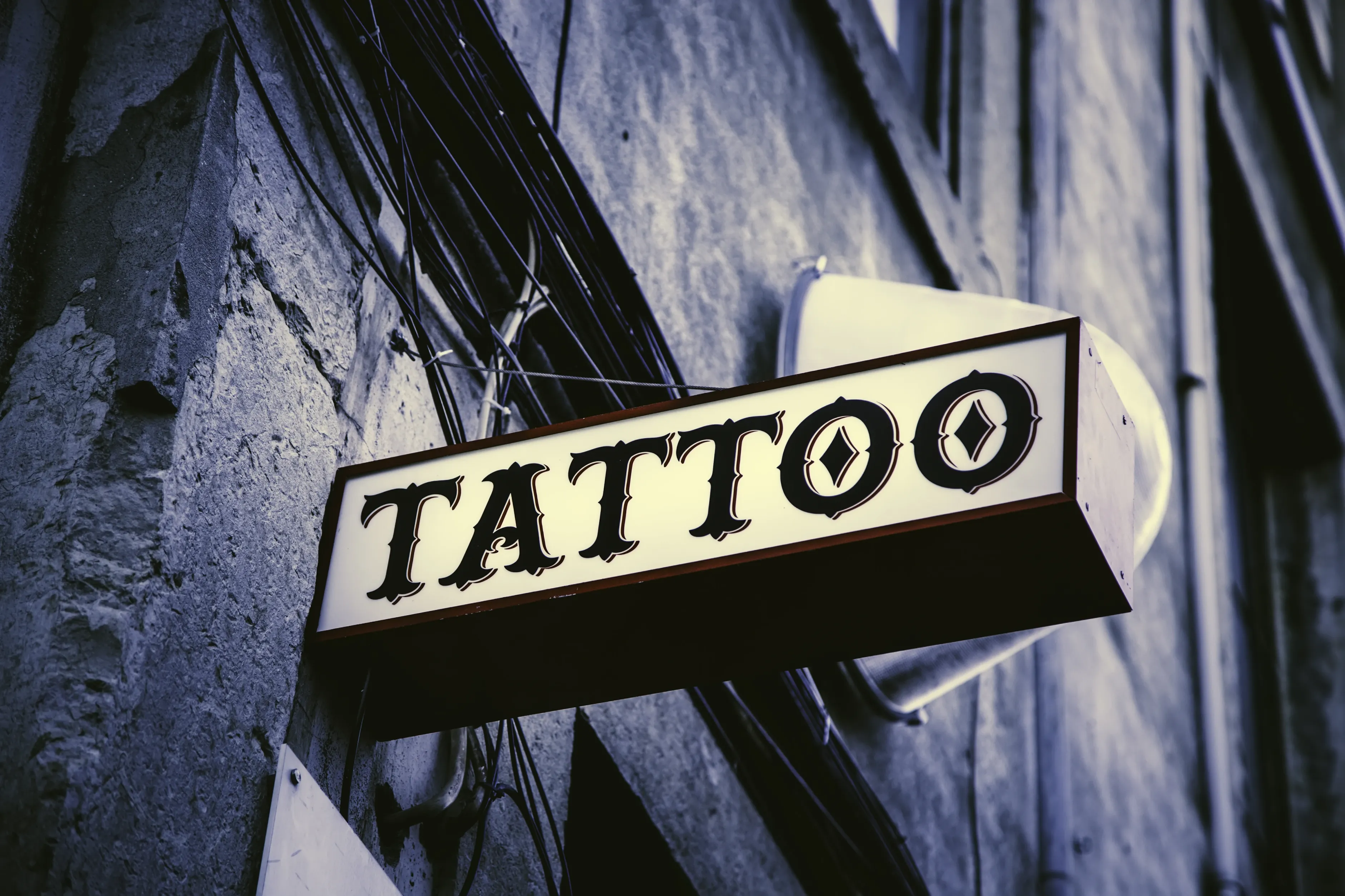Außenansicht eines Tattoostudios mit beleuchtetem TATTOO-Schild